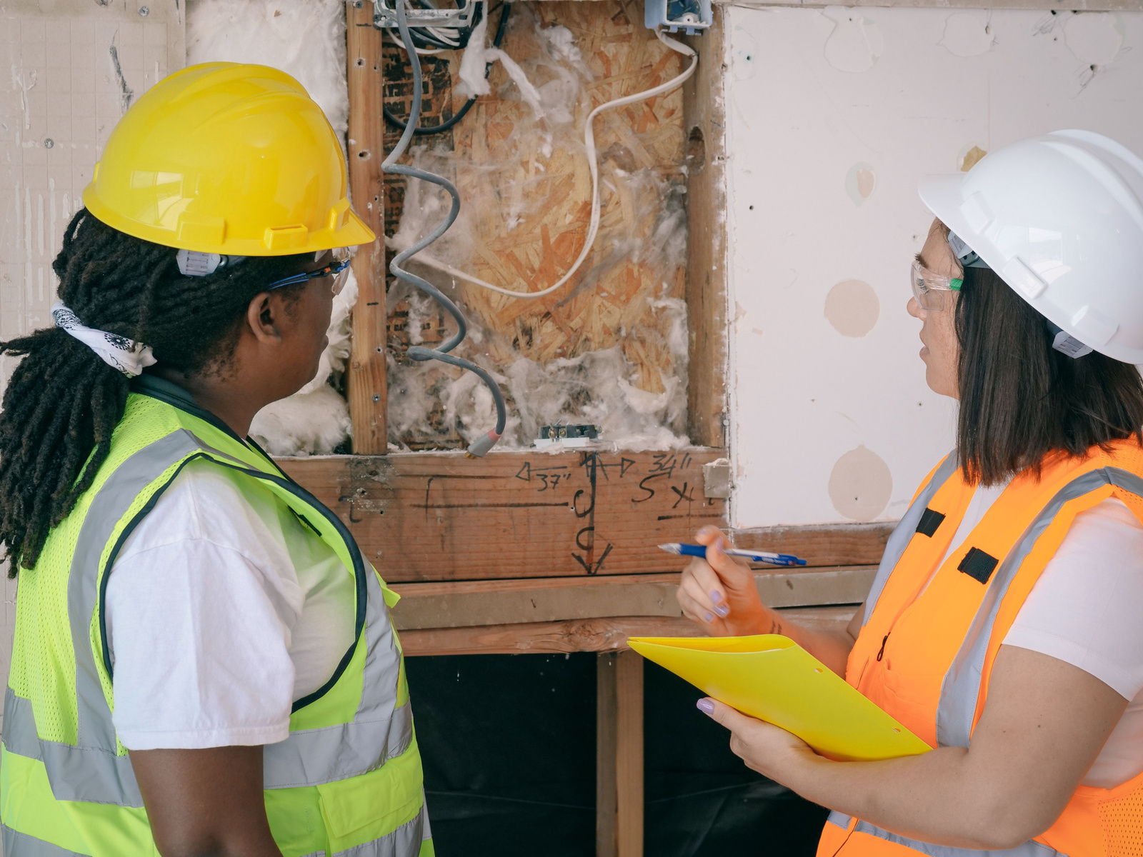 Two people in safety gear examining building conditions